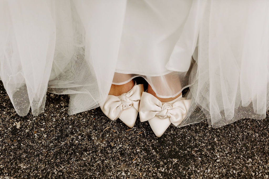 the brides satin, white bowed high heals under her wedding dress