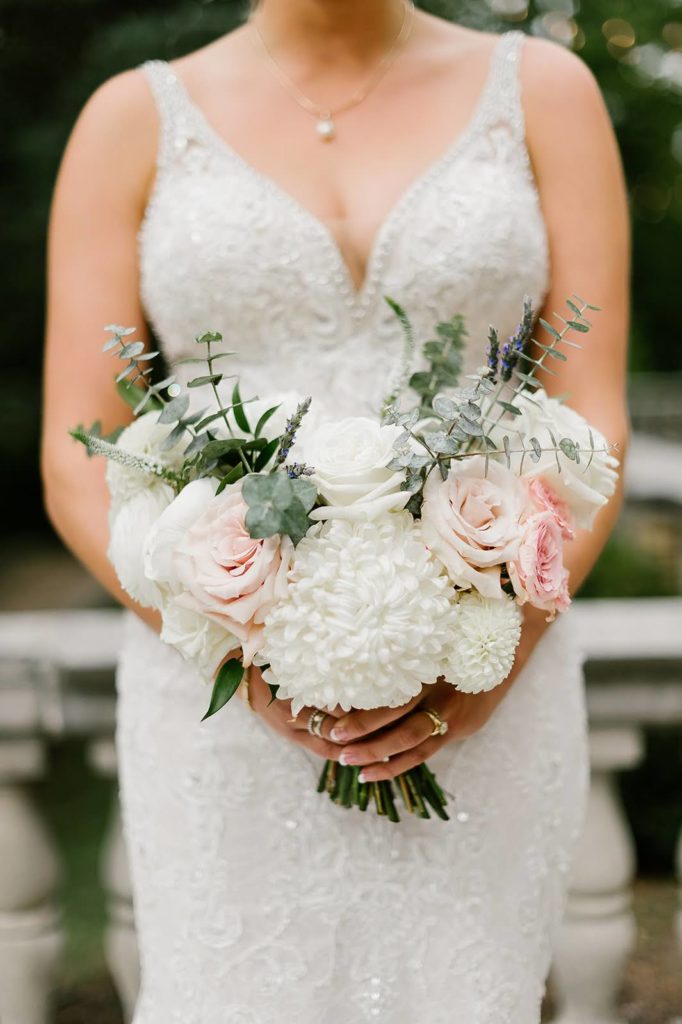 The bride holding her bouquet filled with roses, eucalyptus and dahlias outside Laurel Hall 