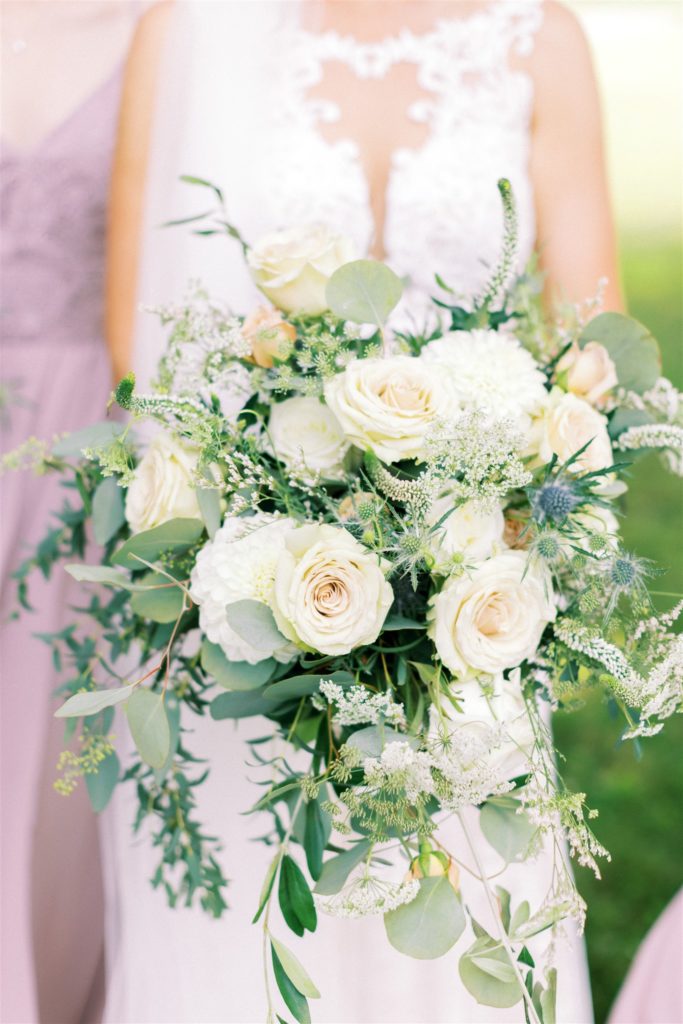 The bridal bouquet with white and peach flowers, greener and hints of blue flowers 