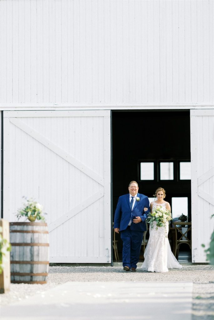 The bride and her father begin to walk down the aisle outside white willow farms 