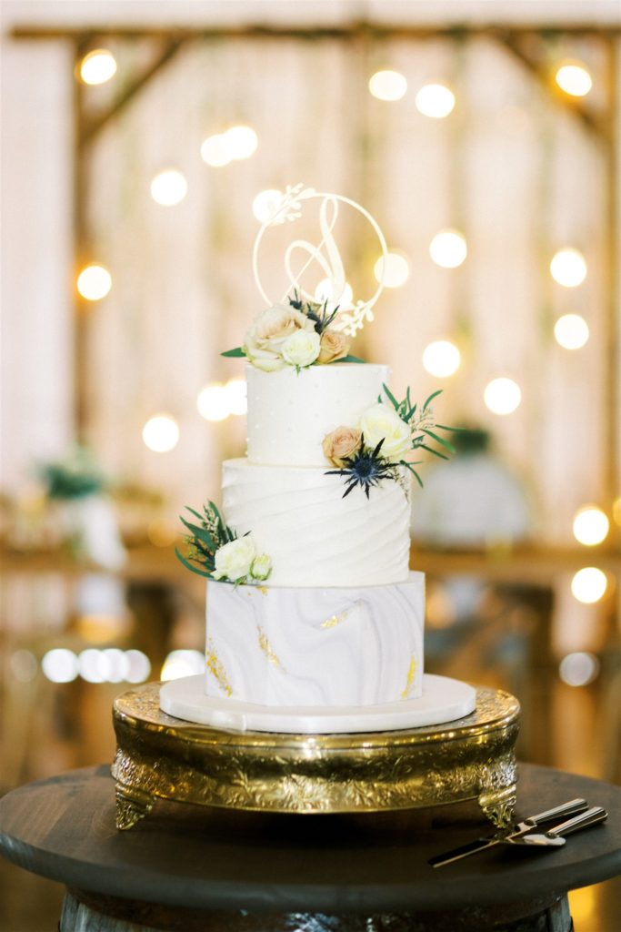 The three tiered white wedding cake had floral accents and a gold accents inside the white willow farms barn 