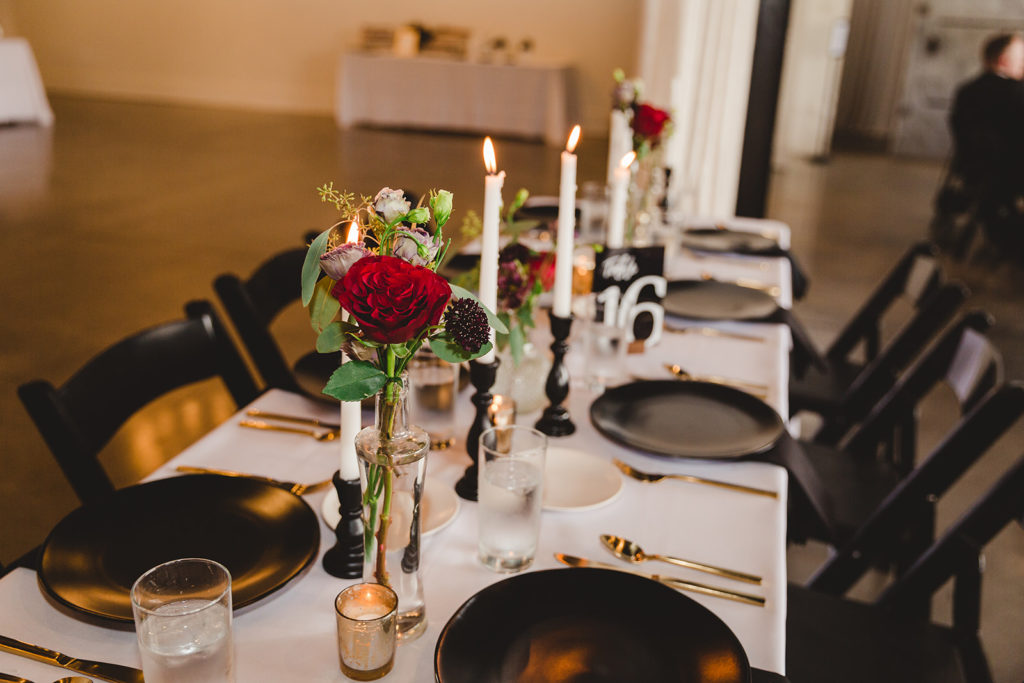 The wedding reception at the Clerestory had red roses, tall candelsticks with black plates and gold silverware. 
