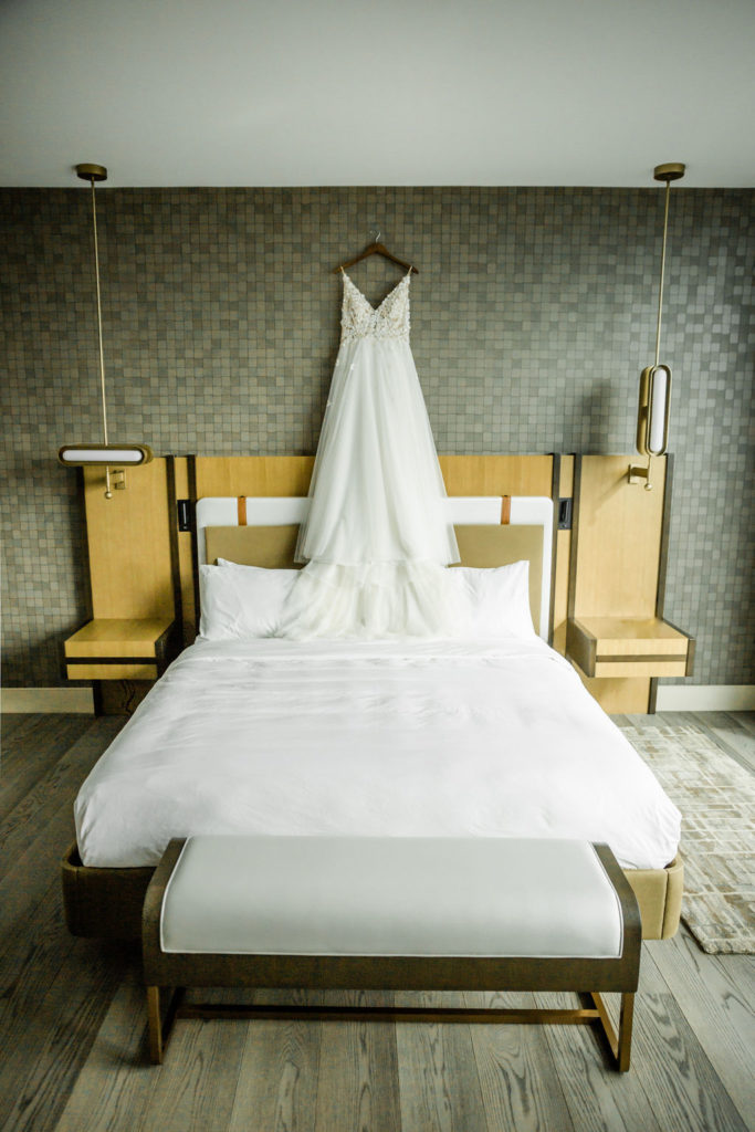 Bridal gown hangs above a hotel bed inside the bridal suite at the Marriott Lexington City Center Wedding venue