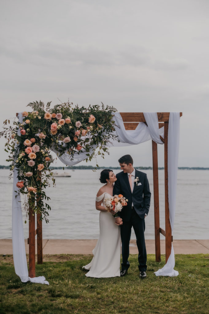 bride and groom embrace under their lake wedding ceremony arch
