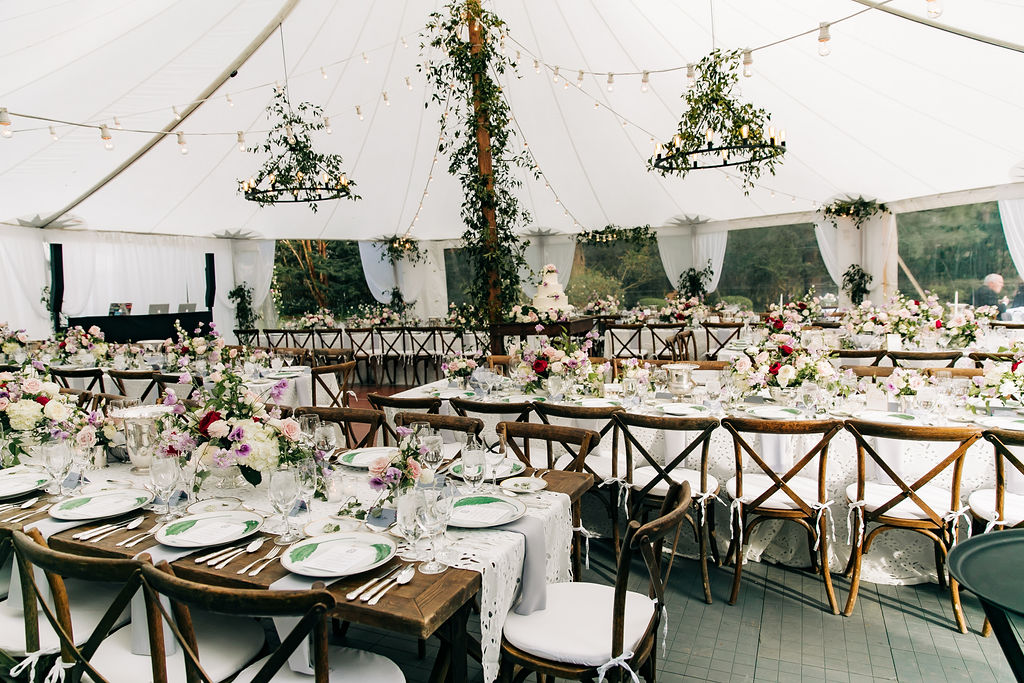 backyard wedding reception layout with long kings tables, a dance floor and white wedding cake in the center