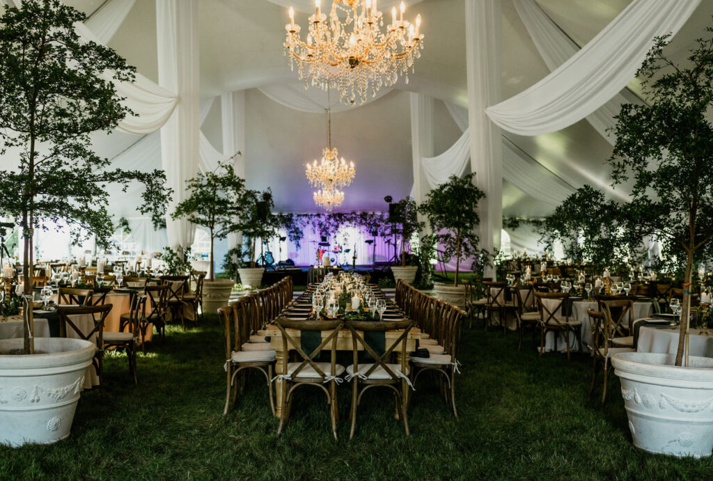 Elegant Backyard Tent Wedding with a black and white stage, chandeliers, and white draping 
