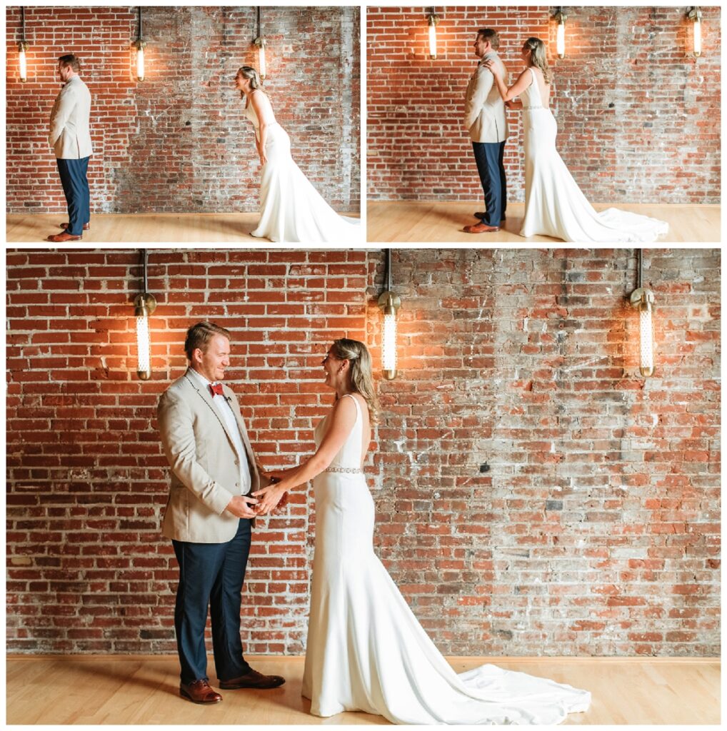 Bride and groom do a first look in front of a red brick wall inside the Frazier history museum 