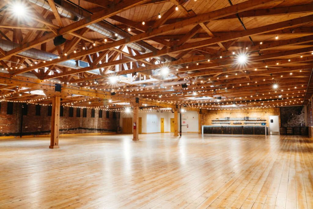Large wedding reception venue with wooden beams, hard wood floors and brick walls. 