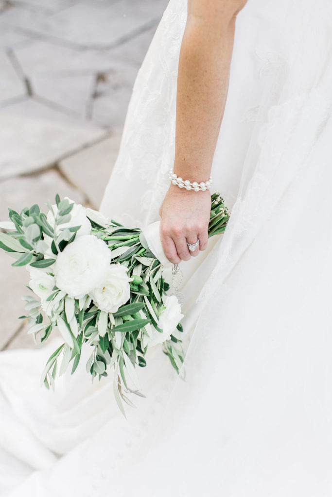 Close up of the bride's diamond ring, pearl bracelet and white and green bouquet