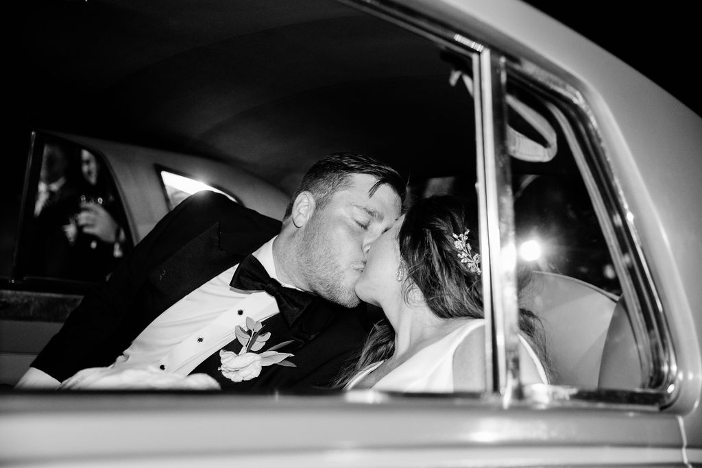 Bride and groom kissing in a car as they drive away from Hurstbourne Country Club in Louisville, Kentucky