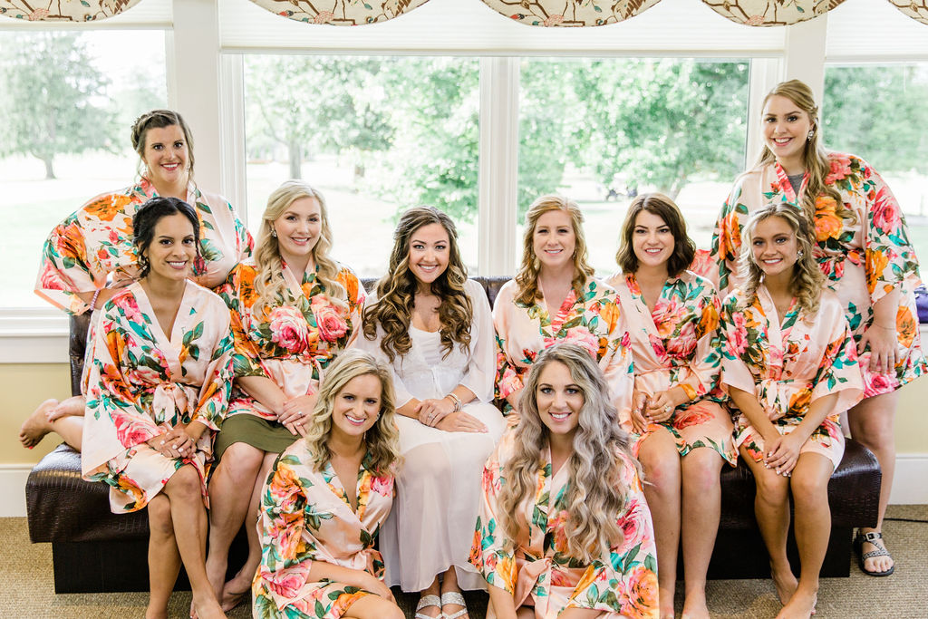 Bridesmaids in their floral robes and the bride in her white robe in the ready room. 