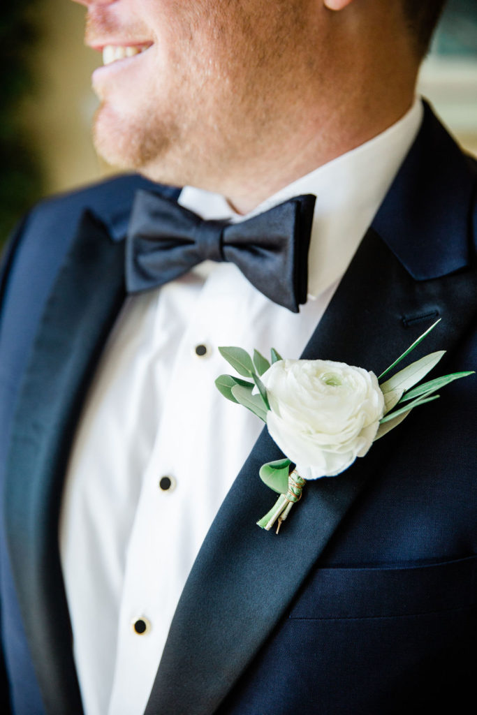 Close up of the Groom's smile, tuxedo and white floral boutonniere. 