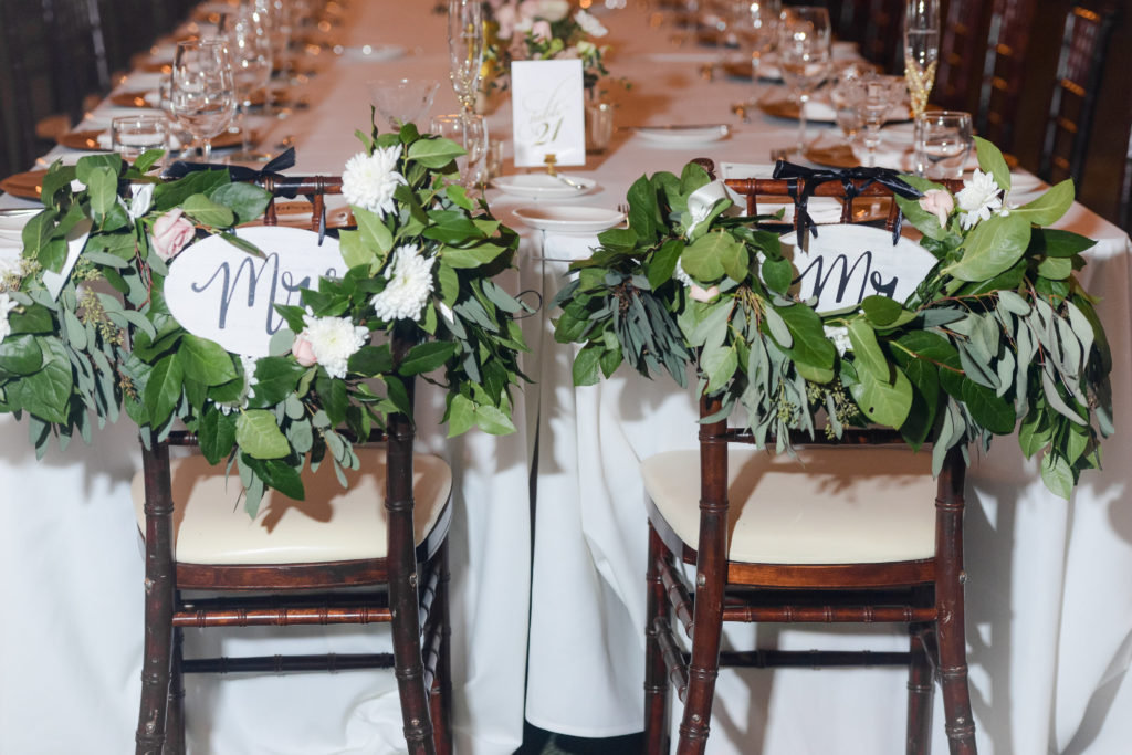 The bride and groom's recetion chairs had greenery and "Mr." and "Mrs." signs hanging behind them