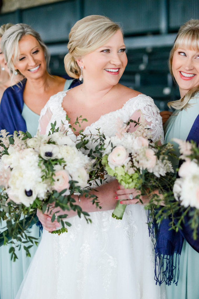 The bride smiling with her bridesmaids with their bouquets