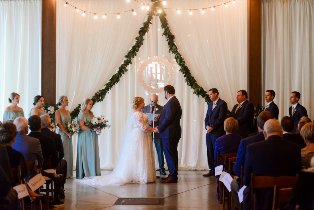 The bride and groom are holding hands at the front of the aisle