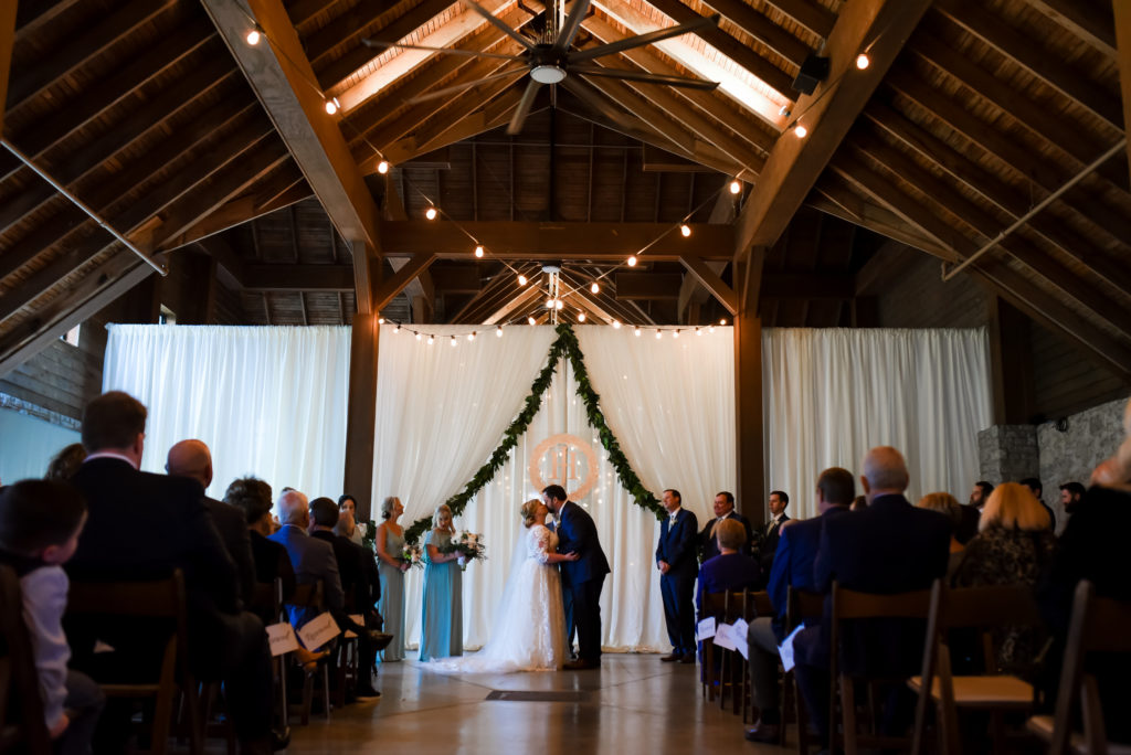 The bride and groom kissing at the end of their wedding ceremony in the Keeneland Barn