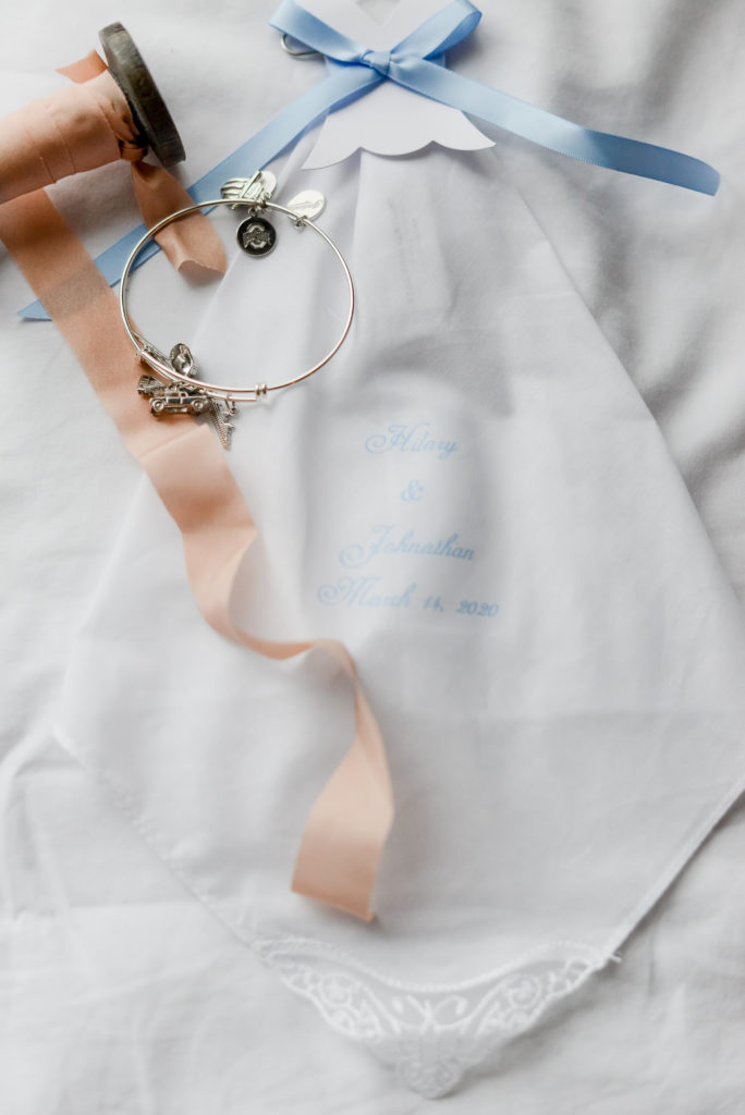 White handkerchief with personalized blue writing and the bride's charm bracelet