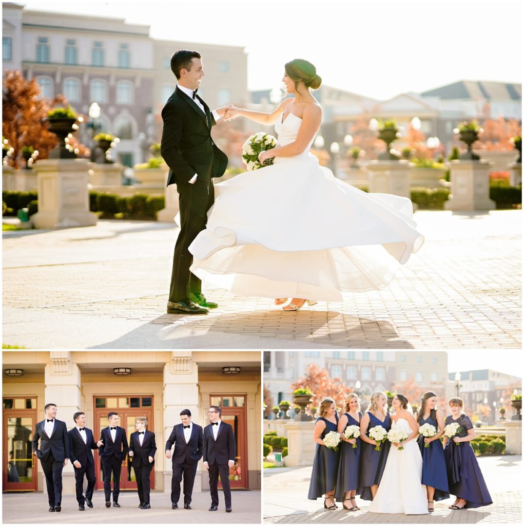 The bride twirls in her dress with help from the groom. The groomsmen are dressed in black tuxedos and the bridesmaids in navy blue dresses with white floral bouquets