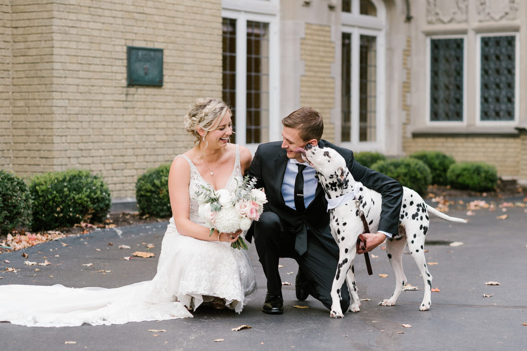 The bride and groom take a sweet picture with their Dalmatian dog outside Laurel Hall