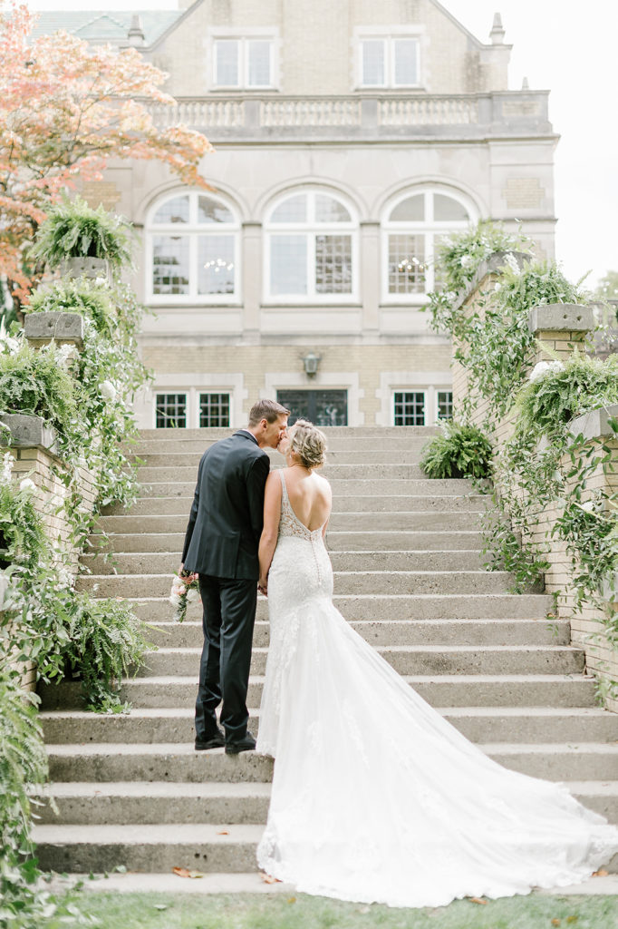 The bride and groom kiss on the outdoor stairs at Laurel Hall in Indianapolis Indiana