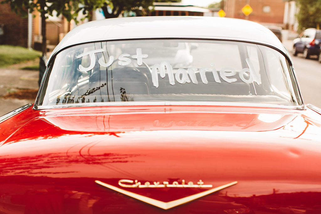 A vintage red Chevrolet car with "Just Married" written on the back window transported the bride and groom from their private property wedding location to their reception