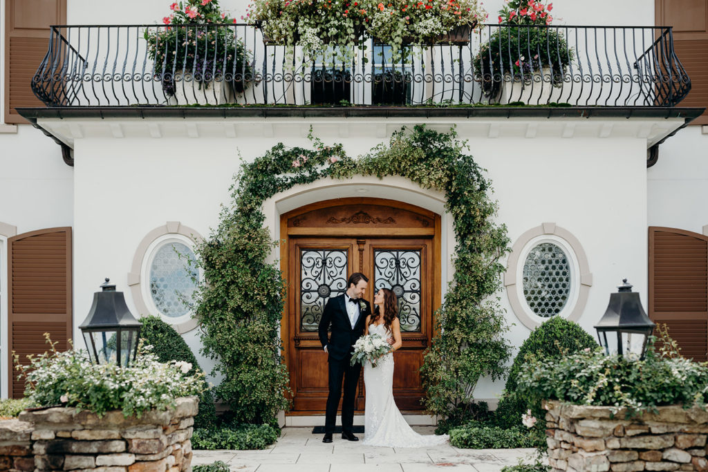 Bride and Groom take a photo in front of a picturesque home on their wedding day at their private property wedding location