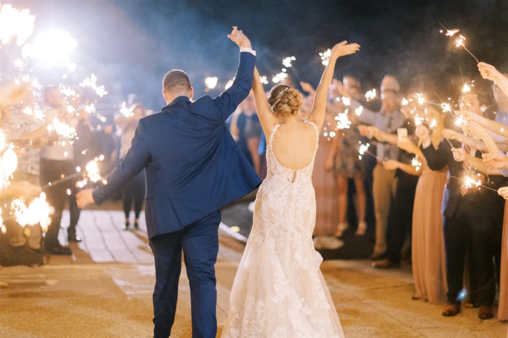 the bride and groom walk through a sparkler tunnel as they exit the white willow farms event barn