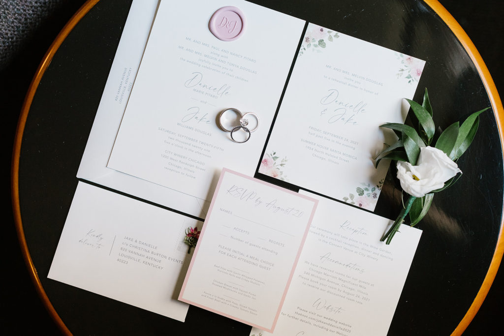 the wedding invitation was laid out with a white flower accent and the bride and groom's wedding rings