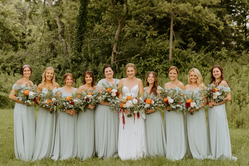 The bride and her bridesmaids take a group photo on the grounds of daniel's vineyard