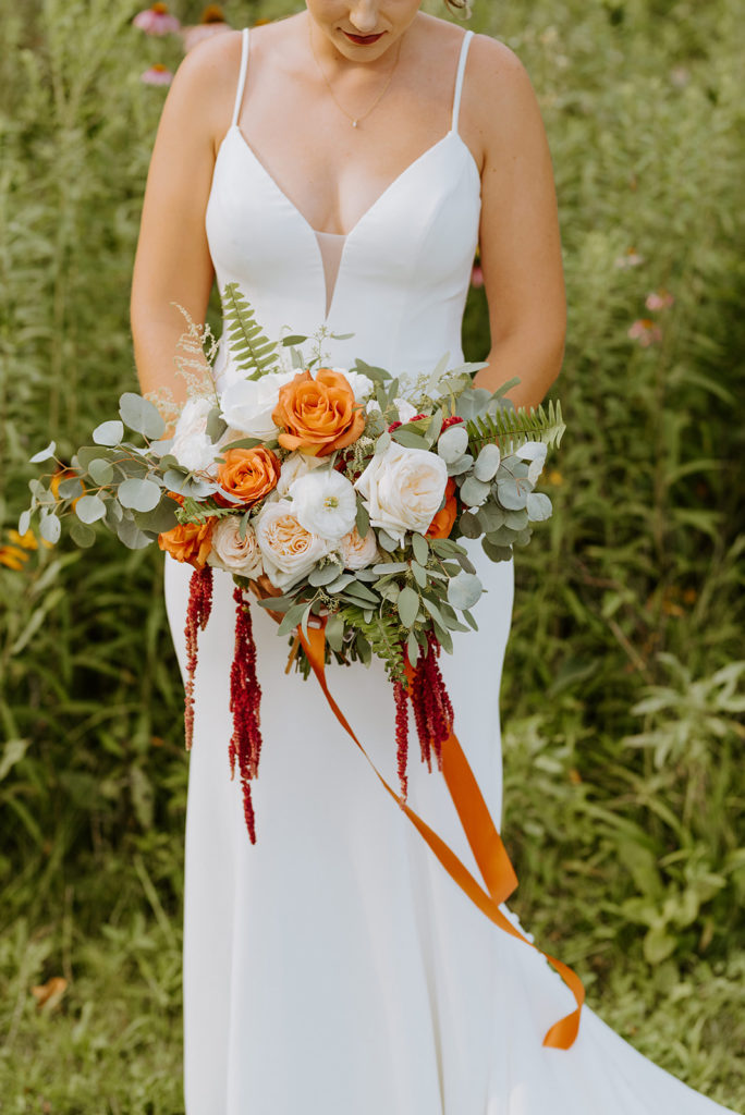 The bridal bouquet filled with white and orange roses, eucaluptus and ferns for this winery wedding