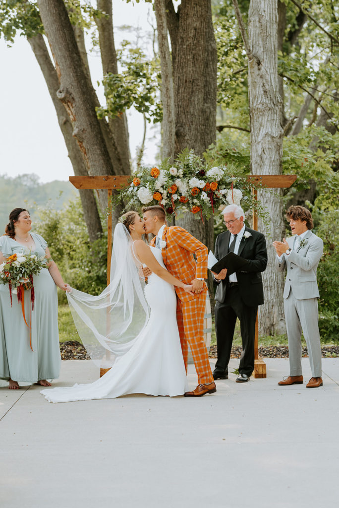 The bride and groom have their first kiss as husband and wife at their outdoor ceremony