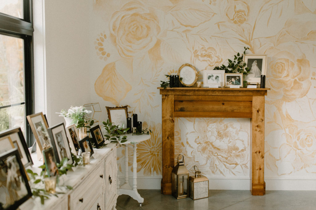 the bridal suite at the wilds wedding venue with flower wall paper, a wooden mantel and vintage photographs