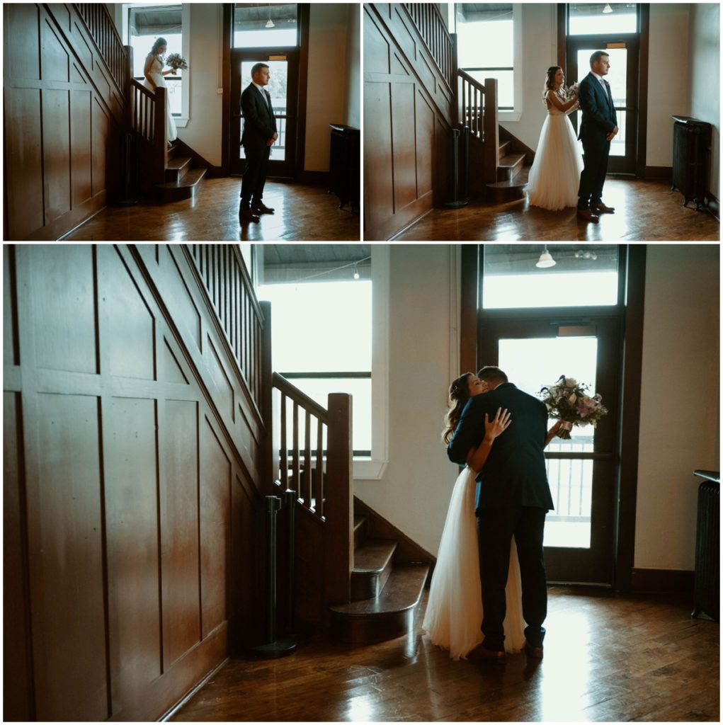 The bride walks down wooden stairs  towards her groom, taps him on the shoulder and they hug for their first look