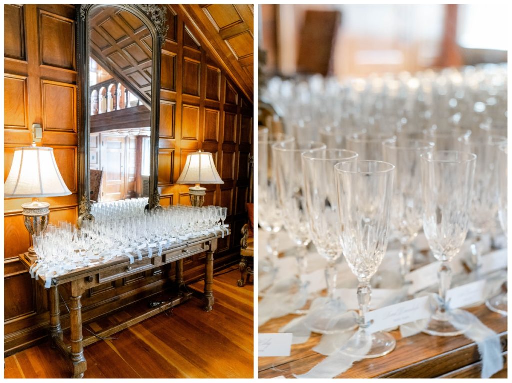 Crystal champagne glasses are set on a wooden table inside Laurel hall for wedding guests 
