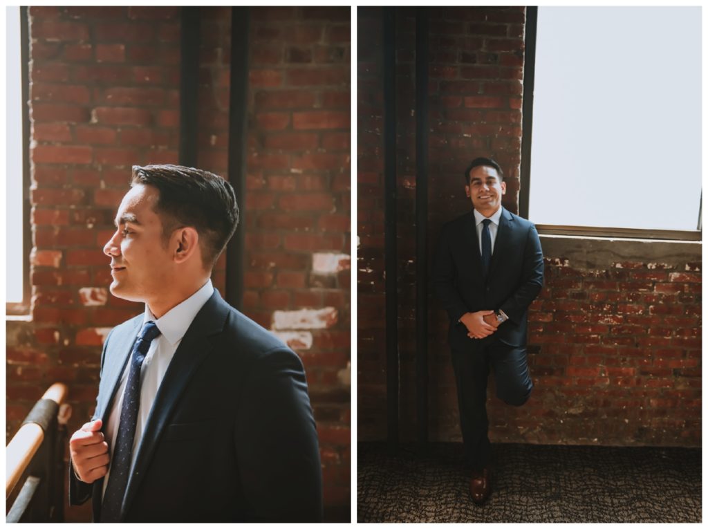 The groom posing in his tux by an industrial brick wall inside The Refinery in Louisville KY 