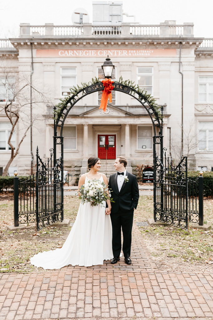 bride-and-groom-portait-at-gratz-park-gate-with-holiday-bow-and-garland