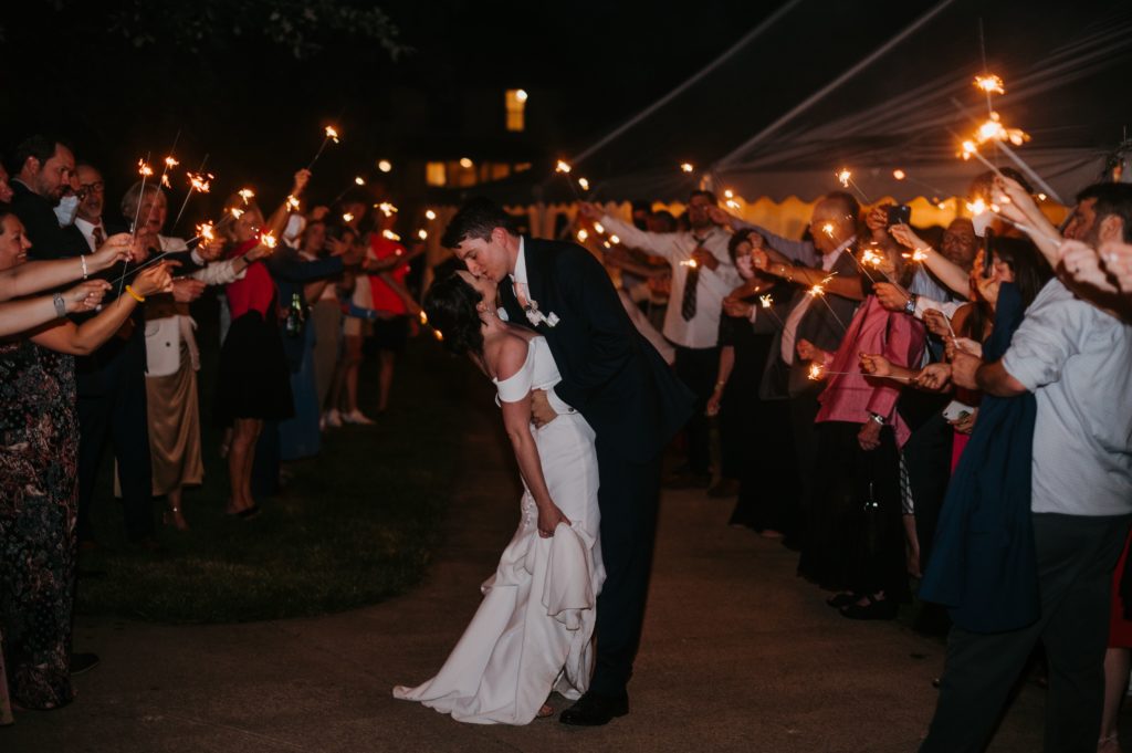 bride and groom kiss as they have a sparkler exit at their wedding at night 