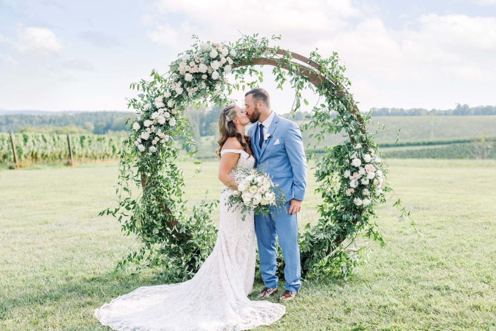 the bride and groom kiss in front of the circular arch 