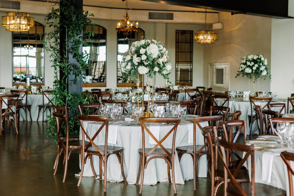 wedding reception at stone tower winery with wood chairs, cream linens, tall floral centerpieces with white flowers and greenery