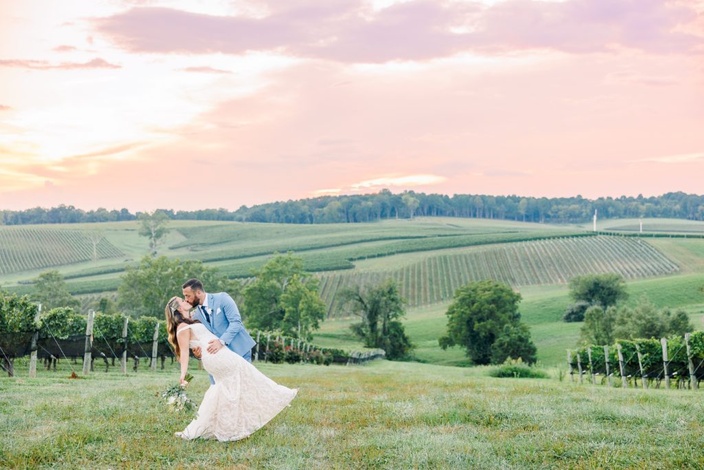 bride and groom kiss at sunset overlooking the vineyards 