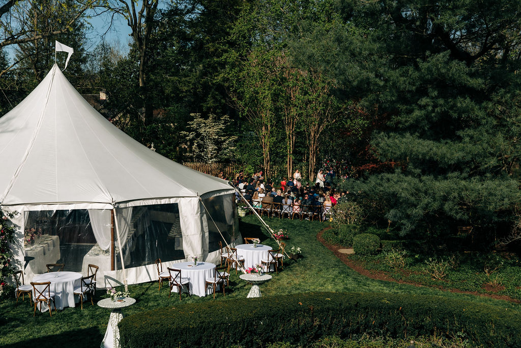 wedding ceremony in a back yard with a large white tent with the reception