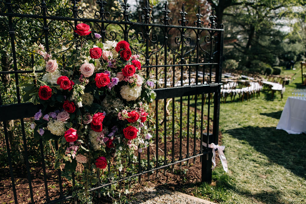 flower arrangement on a rod iron black gate as an entry way to a wedding ceremony