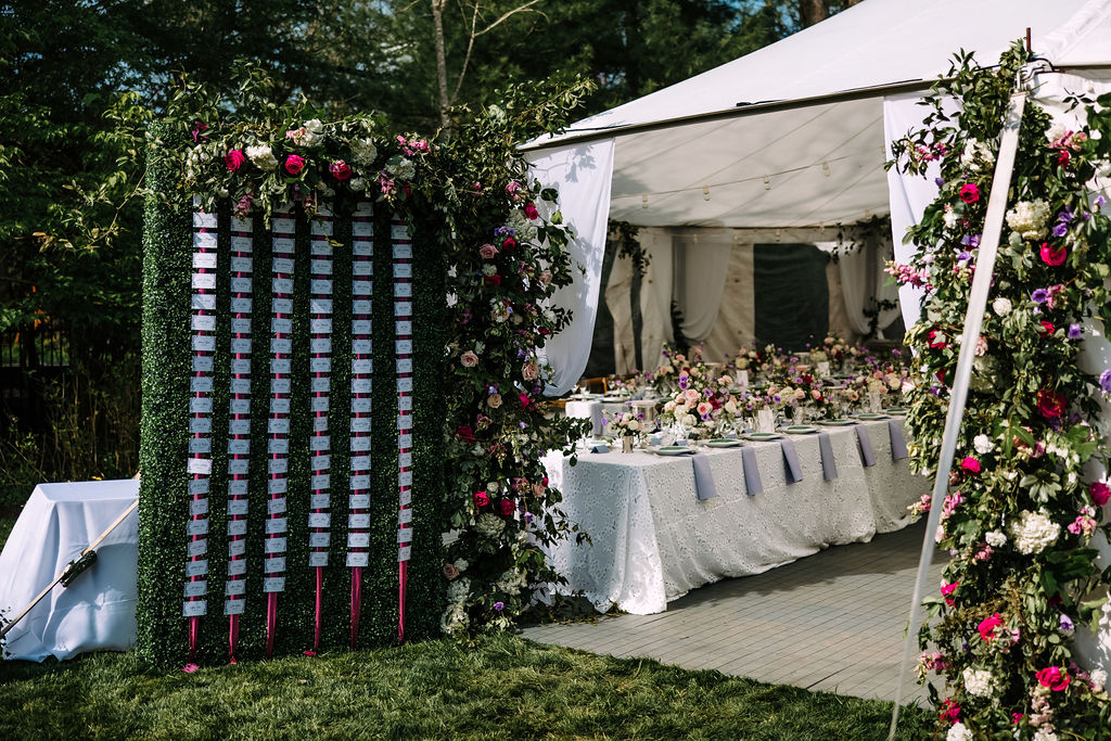 entrance to the reception tent had a large seating chart and standing flower arrangements