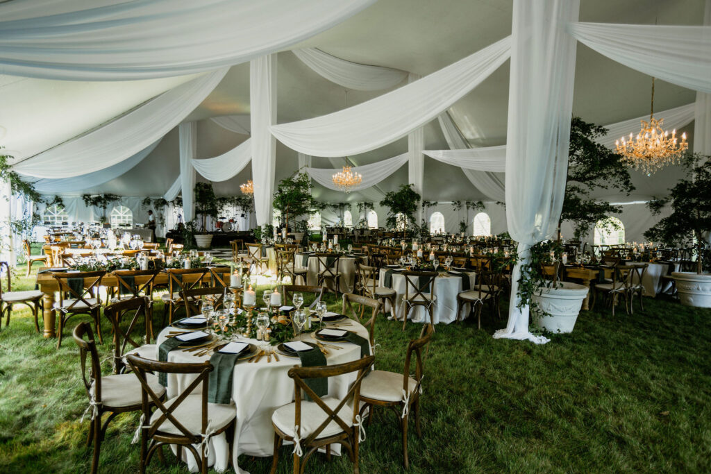 Elegant Backyard Tent Wedding  with white draping, round and long tables, chandeliers and faux trees