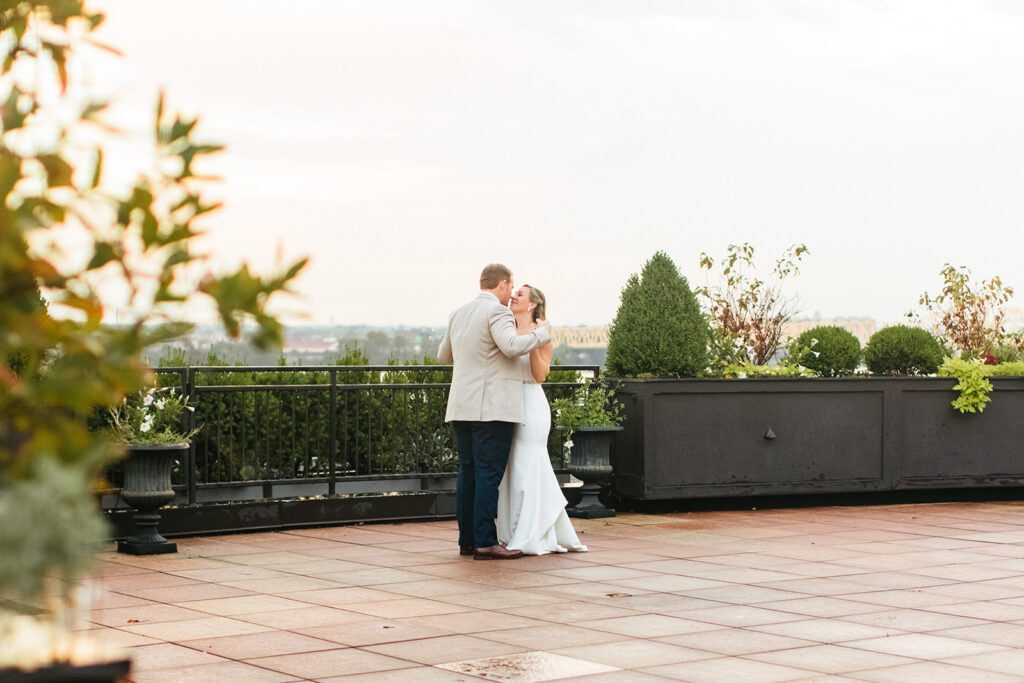 Bride and groom stand together on the rooftop of the Frazier History Museum with the Louisville skyline in the background at sunset 