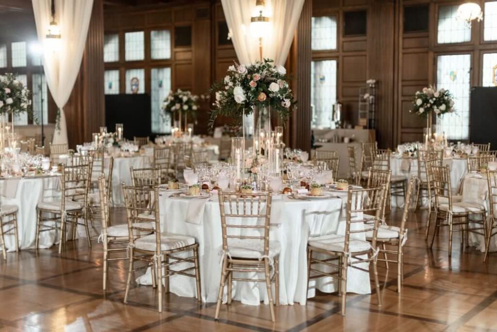 Wedding reception table inside scottish rite cathedral with tall floral centerpieces, gold chairs and beautiful decor